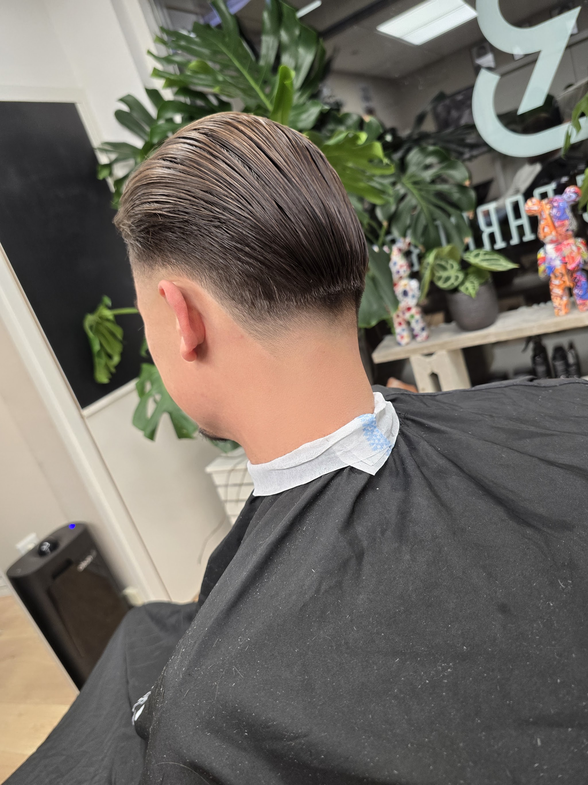 Afgewerkte fade met naar achteren gekamd haar, klant van achteren gezien in de stoel